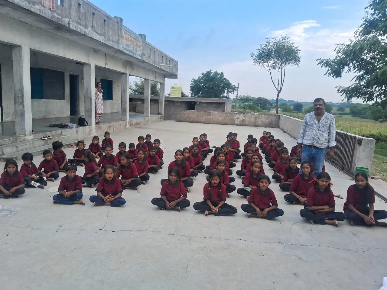 Students in school uniform seated in rows for morning assembly in the courtyard of Dindayal Ashram Shala, Malvasi.